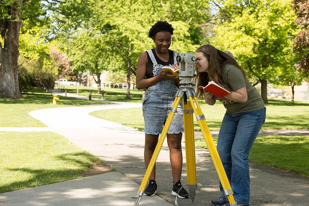 two civil engineering students using land surveying equiptment